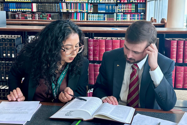 Two students reading a law textbook together in a 法律图书馆.